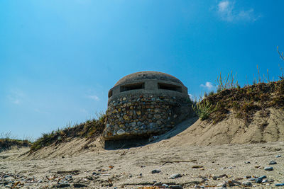 Old ruins on beach against blue sky