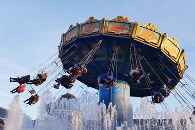 Low angle view of chain swing ride against sky