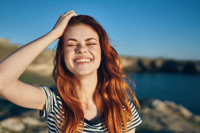 Portrait of smiling young woman against sky