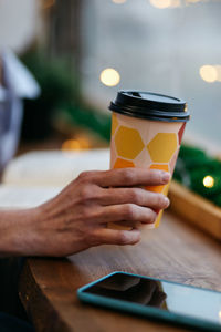 Cropped hand of woman with cup of coffee, using mobile phone