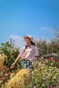 Woman standing by flowering plants against sky