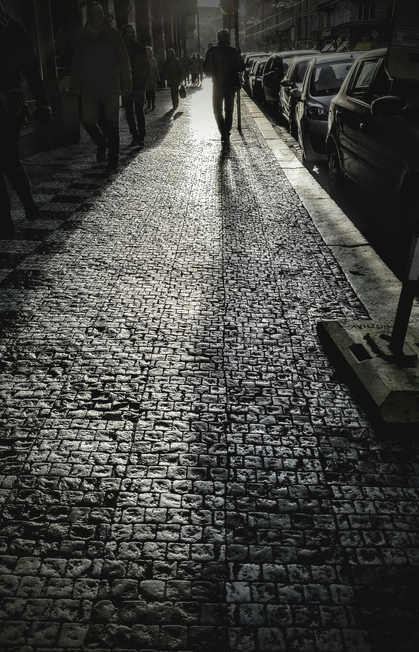 HIGH ANGLE VIEW OF PEOPLE WALKING ON COBBLESTONE