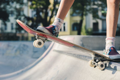 Legs of a skater girl on the skateboard before doing a drop in at the skate park bowl