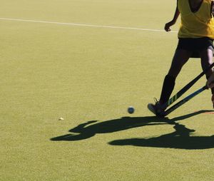 Low section of women playing hockey on field