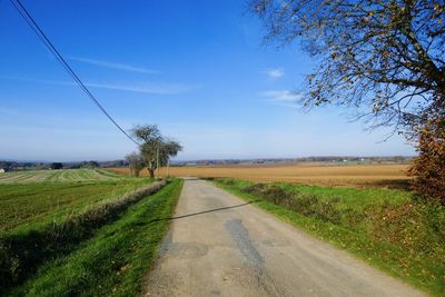 Road amidst field against sky