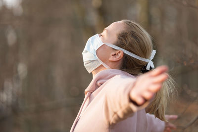 Side view of woman wearing mask standing outdoors