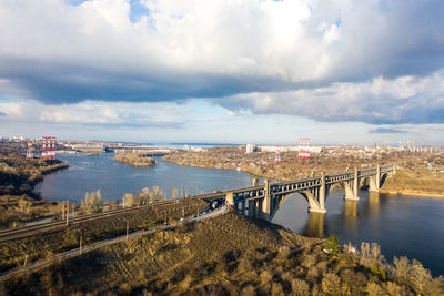 Bridge over river against cloudy sky