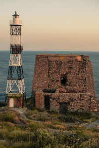 Old tower by sea against sky