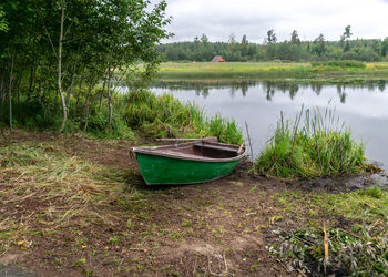 Boat moored on shore by lake against sky