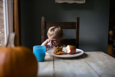 Upset toddler eating a snack at the table