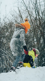 Siblings playing in snow during winter