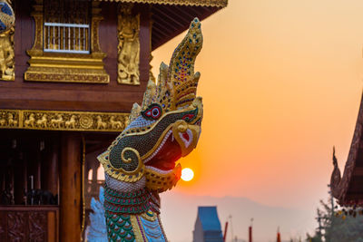 Low angle view of statue against temple during sunset