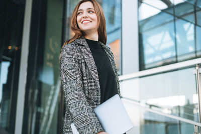 Portrait of young woman standing in city