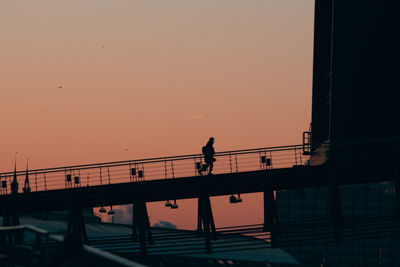 Silhouette man on bridge against sky during sunset