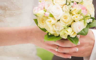 Cropped image of newly wed couple holding flower bouquet