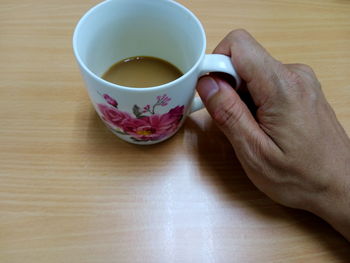 Midsection of person holding tea cup on table