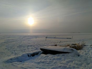 Scenic view of snow covered land against sky during sunset