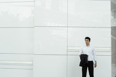 Full length of a young man standing against wall