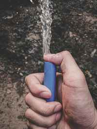 Close-up of man holding garden hose with flowing water