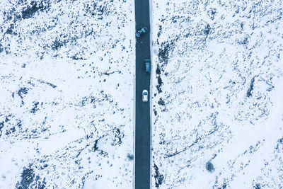 Aerial view of road amidst snow covered fields