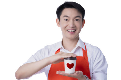 Portrait of smiling man holding camera against white background