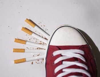 Close-up of canvas shoe on cigarettes