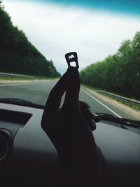 Close-up of hand holding car on road