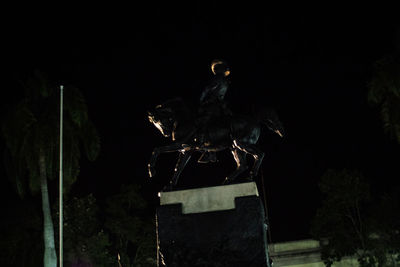 Low angle view of illuminated lighting equipment against sky at night