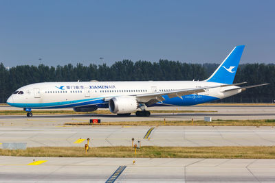 Airplane on airport runway against clear blue sky