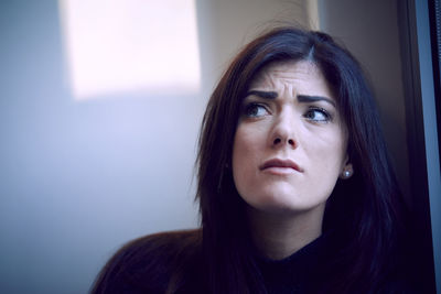 Close-up portrait of a young woman looking away at home