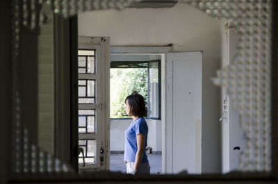 Young woman looking through window