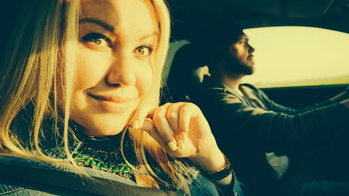 Portrait of smiling woman sitting with man in car on sunny day