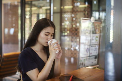 Young woman drinking glass on table at restaurant