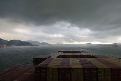 Container ship in sea against cloudy sky