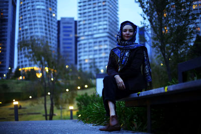 Portrait of woman sitting in city at night