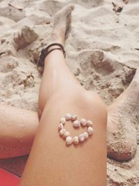 Low section of woman standing on sand