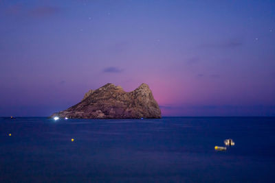 Scenic view of rocks at sea against sky at night