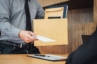 High angle view of employee giving resignation to manager on table in office