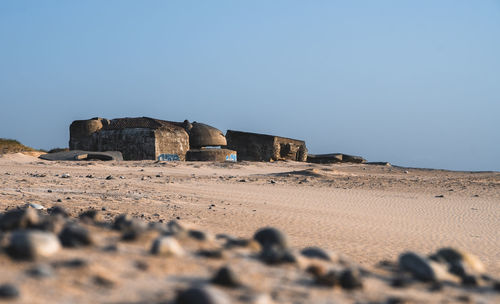 Stone wall on sand against clear blue sky