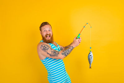 Full length of a young man holding yellow background