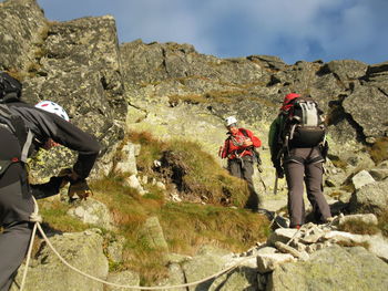 Low angle view of men on mountain against sky