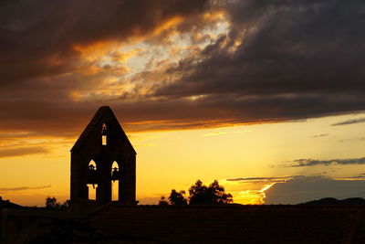 Silhouette building against dramatic sky during sunset
