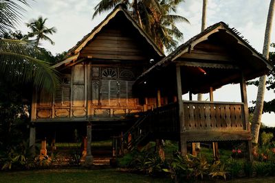 Built structure with palm trees against sky