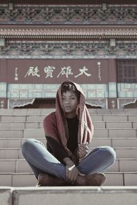 Portrait of young woman wearing scarf while sitting on steps