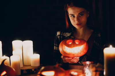 Portrait of woman holding illuminated string lights at home