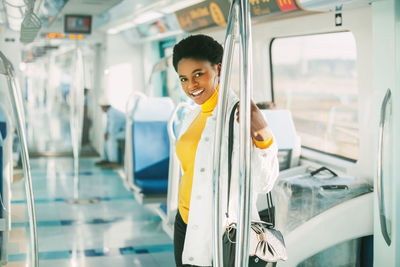 Portrait of smiling woman standing in bus