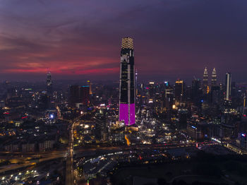 Illuminated modern buildings in city against sky at night