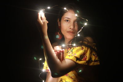 Young woman holding illuminated string lights