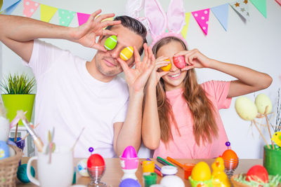 Father and daughter holding easter egg in front of face