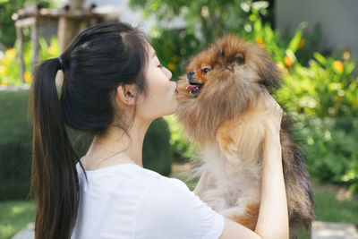 Young woman holding dog standing at park